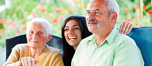 A close-cropped shot of a dark-haired woman sitting between her aging parents.