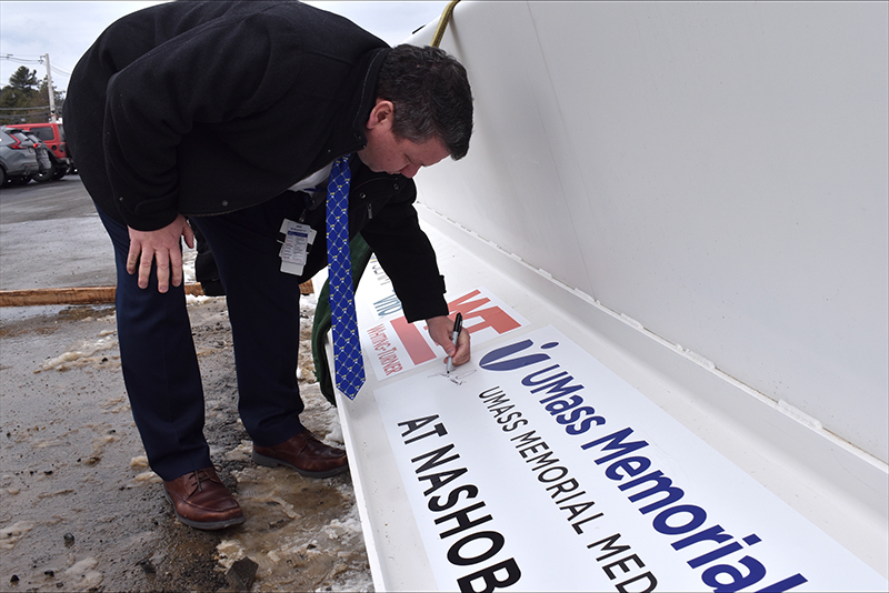 Justin Precourt, signs the banner that will appear at the top of the facility's frame.