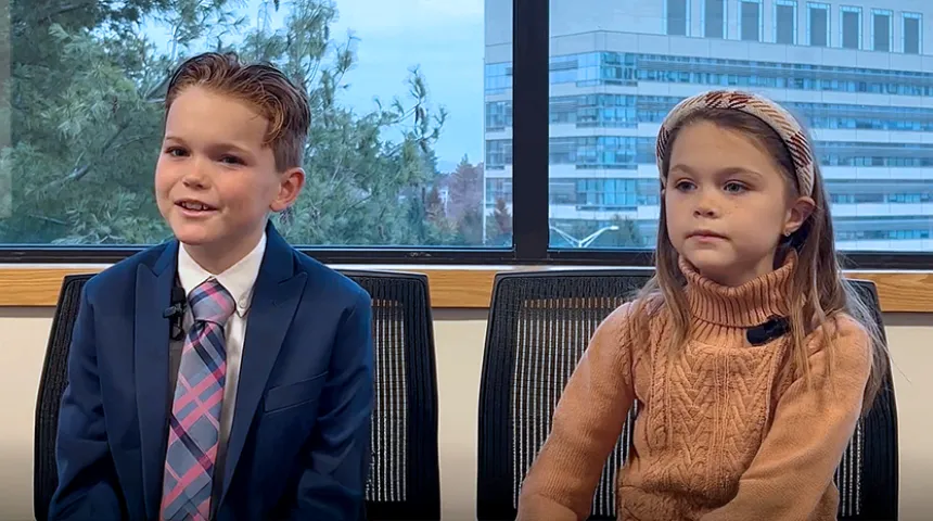 John and Maeve Aiello telling their story with the medical center showing in the window behind them.