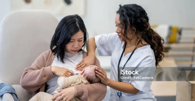 A new mother gets assistance from a caregiver in learning to breastfeed.