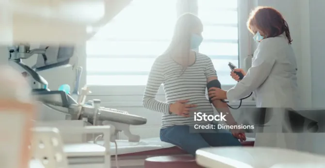 A pregnant woman gets her blood pressure checked in the exam room.