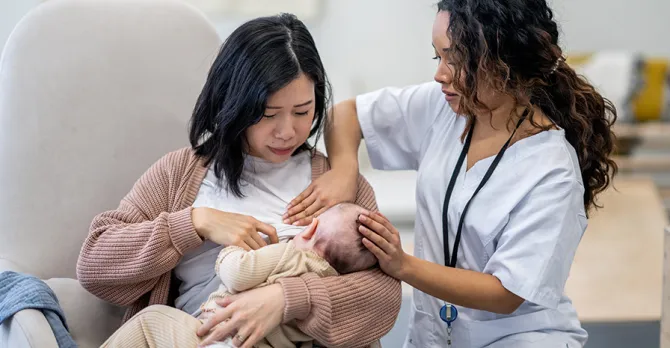 A new mother gets assistance from a caregiver in learning to breastfeed.