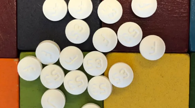 Multiple white pills are on top of different-colored blocks.