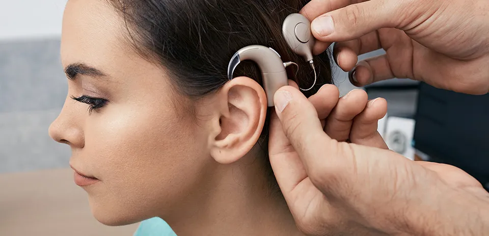 Having recovered from the cochlear implant surgery, a young female patient has her sound processor fitted behind her ear.