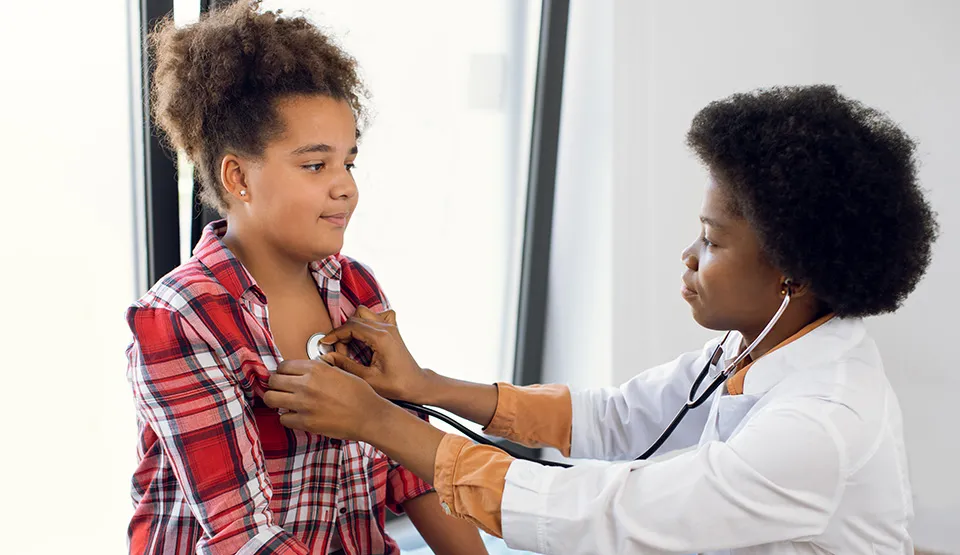 An adolescent being examined by a doctor.