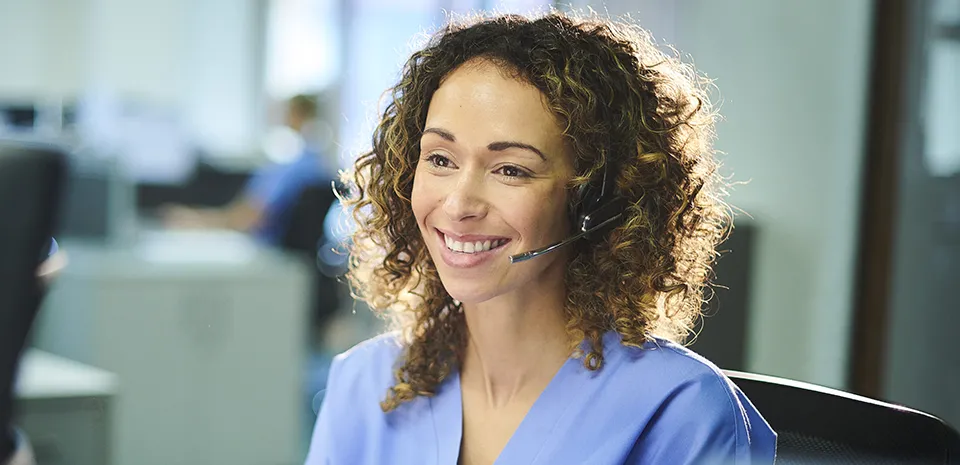 A smiling customer service representative wearing a headset looks forward.