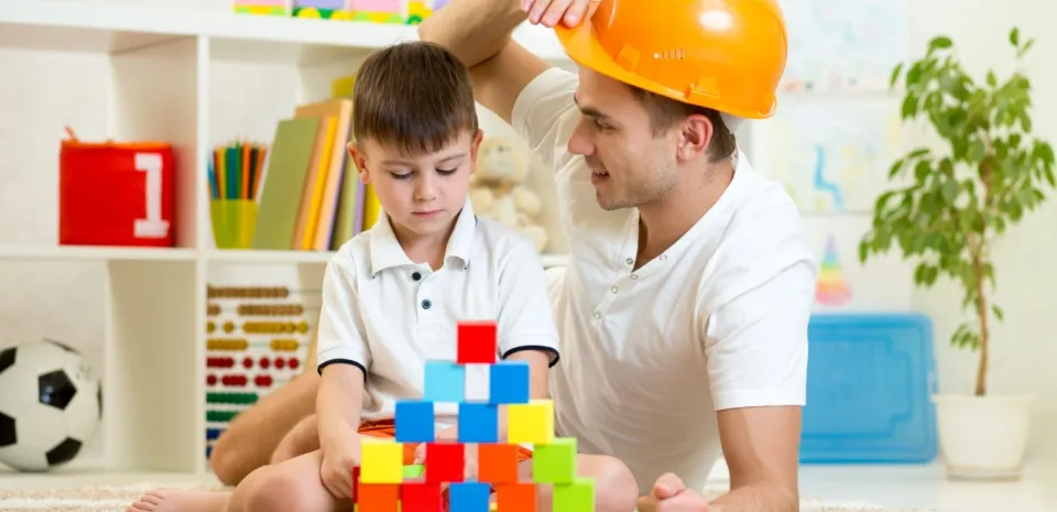 father playing blocks with his son on the floor to benefit son's mental health