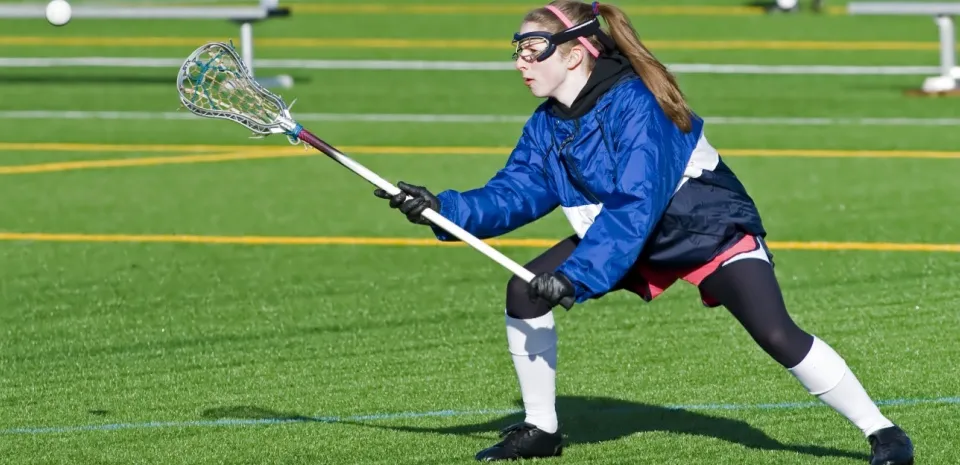Teen girl playing lacrosse on a green field