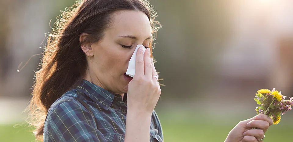 girl blowing nose and sneezing from pollen
