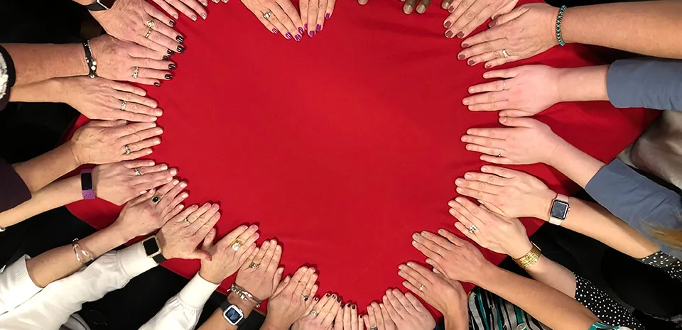 group of people putting hands together to shape a heart