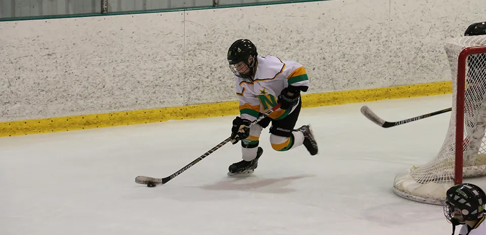 young boy playing hockey, skating with the hockey puck