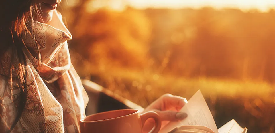 girl relaxing drinking tea and reading a book in the sunlight