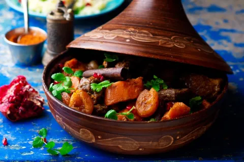 lamb and butternut squash and apricots in a tagine on a blue tablecloth