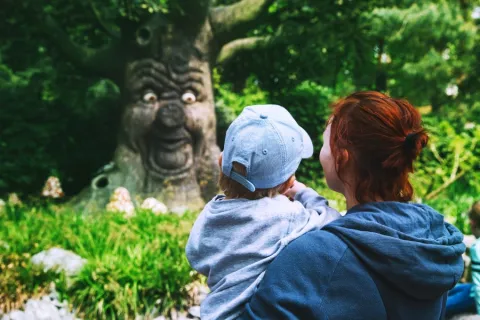 mom holding toddler near tree with a funny face sharing childhood myths