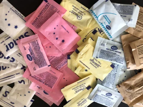 several different colorful sweetener packets on a table