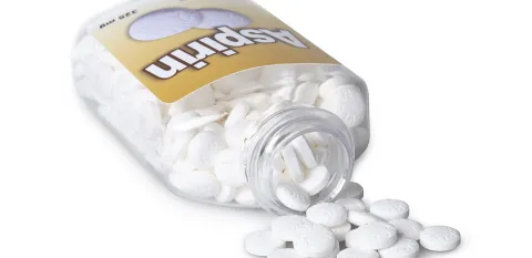 bottle of aspirin is tipped over with some pills outside of the bottle