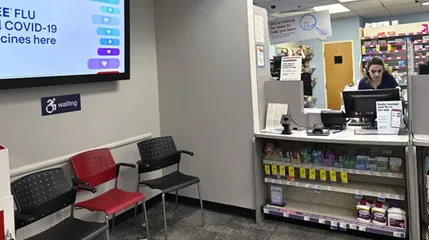 A pharmacy staffer works online at the counter of a retail pharmacy.
