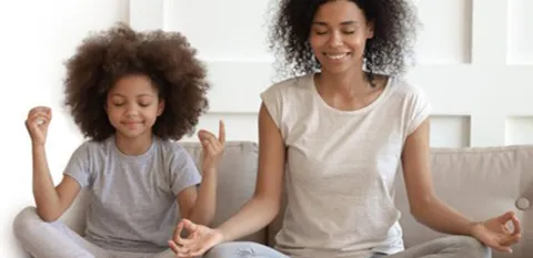 diverse mom and daughter mediating in their living room