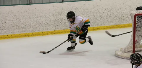 young boy playing hockey, skating with the hockey puck