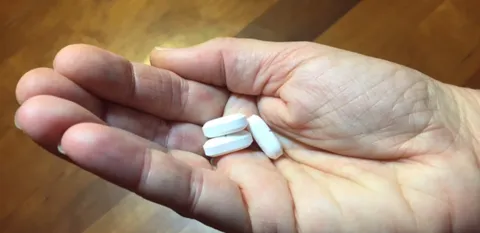 hand holding 3 white pills