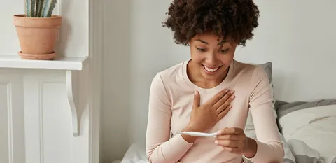 young woman excited and reading pregnancy test