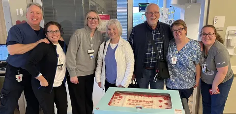 Donald "Jeff" Lawrence poses in front of the large cake he brought to visit the LVAD Program and cardiac care teams who helped him to recover after surgery.