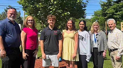 Outside on the grounds of Milford Regional Medical Center, the three scholarship recipients stand with those responsible for supporting the scholarship and with the director of Volunteer Services.