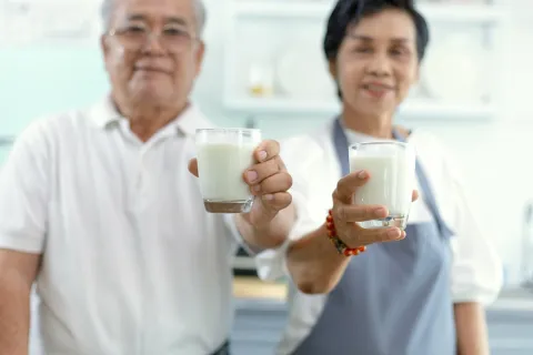 A man and women are both holding glasses of milk.