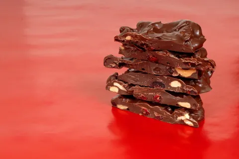 A stack of chocolate cherry bark is on a red table.