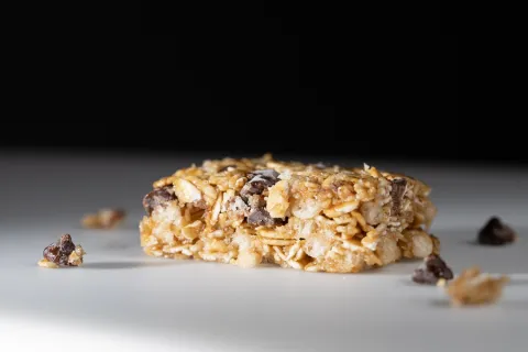 A closeup of a granola bar is shown against a black background.