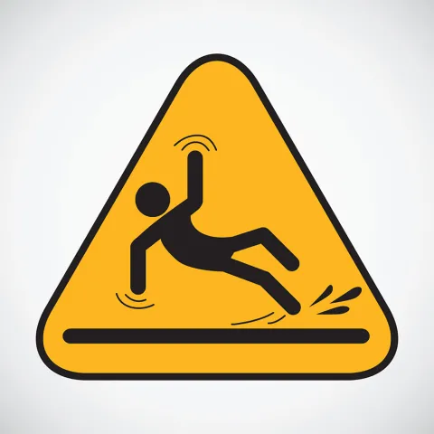 A triangular yellow sign shows a stick figure slipping on a wet surface.