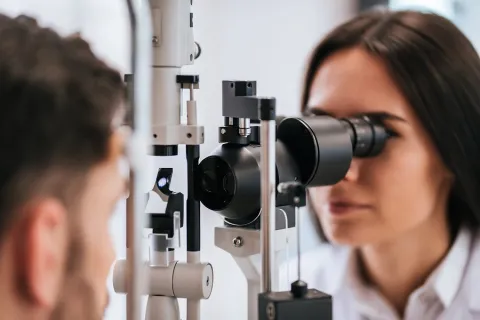 A female optometrist is giving an eye exam to a male patient.