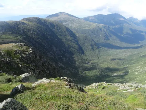 A large green valley is shown from atop a mountain on the Jewell Trail in the Presidential Range of the White Mountains.