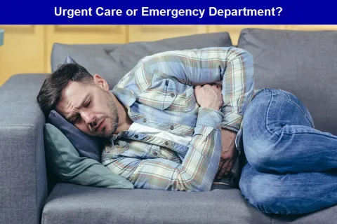 A man lays on a sofa, in the fetal position, while clutching his abdomen.