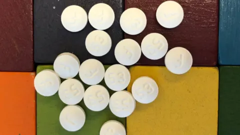 Multiple white pills are on top of different-colored blocks.