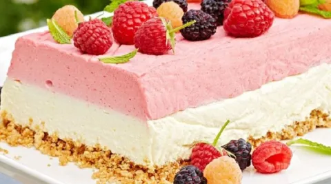 Berries are on top of and around a pink and white icebox cake.
