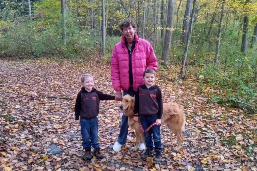 Female patient Jawan Betts holding two young children's hands with their Golden Retriever nearby