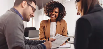 A couple signs a contract at a representative's desk.
