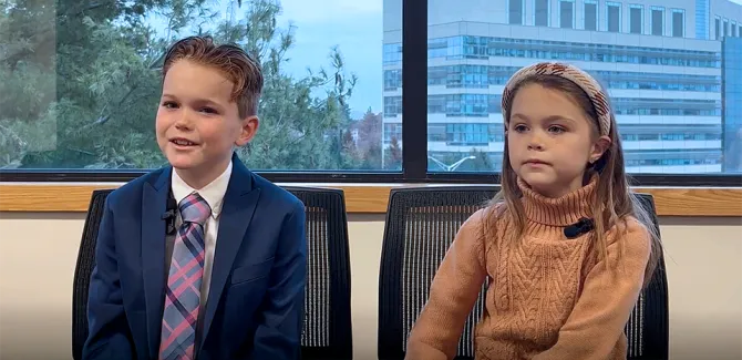 John and Maeve Aiello telling their story with the medical center showing in the window behind them.