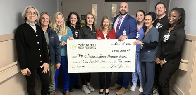 A group of caregivers at the Marlborough Campus hold up a large-size check.