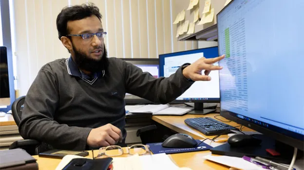 Mohammed Salman Shazeeb, associate professor of radiology at UMass Chan Medical School, points to his computer screen from behind his desk and shows the results of his research on AI and breast cancer.