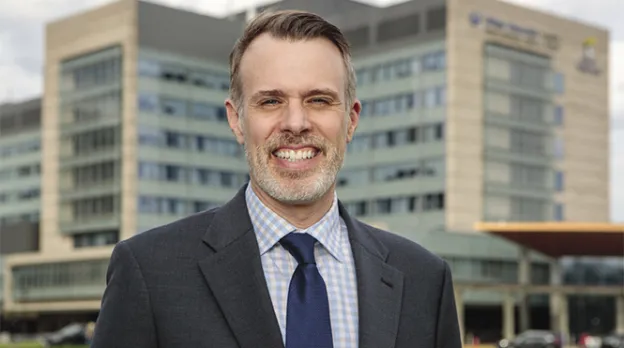 Dr. David McManus, incoming chancellor of UMass Chan Medical School, stands on the grounds of UMass Memorial Medical Center, with the main entrance to the hospital behind him.