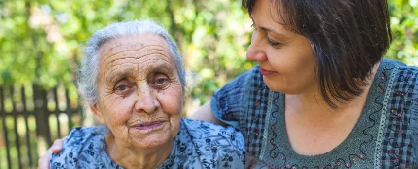 Loving daughter puts arm around elderly mother as she avoids caregiver burnout