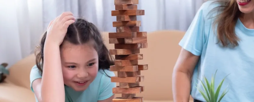 mother and daughter playing jenga on a table lessening screen time
