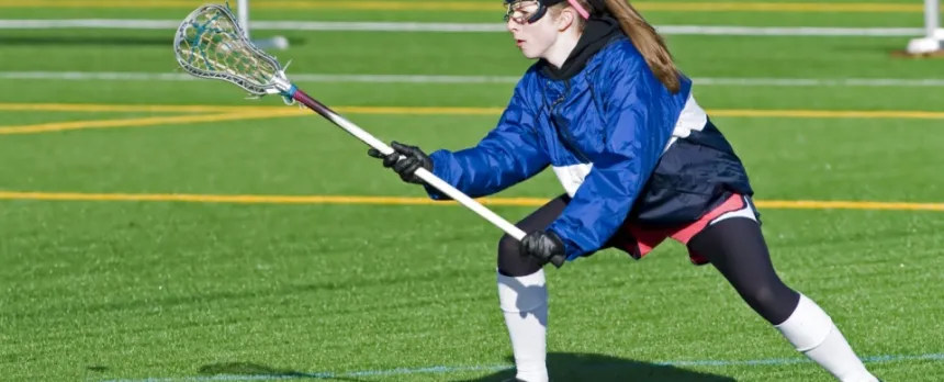 Teen girl playing lacrosse on a green field