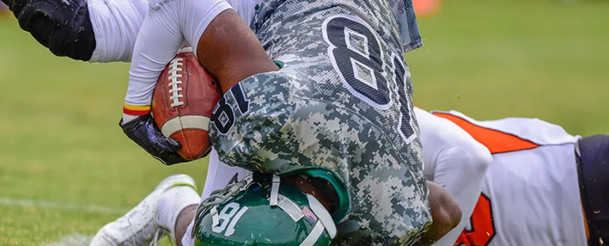 football players tackling one another while playing in a football game