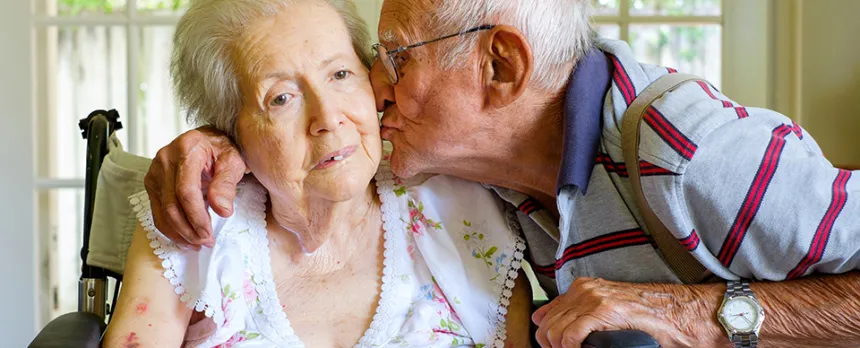 elderly man kissing his wife on the cheek