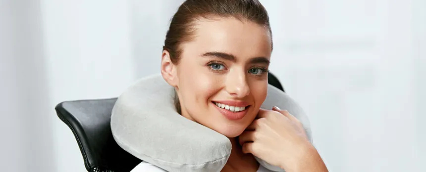young woman sitting in chair with gray neck pillow around her neck