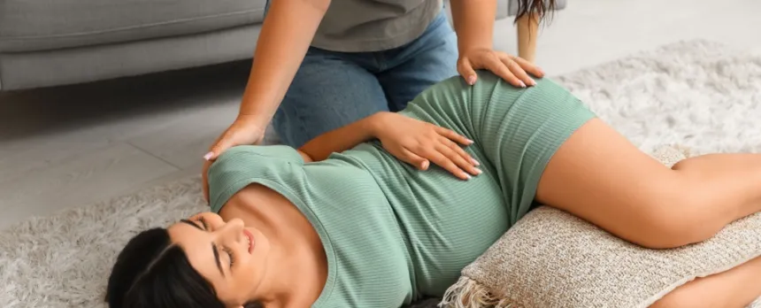 Doula relieving pregnancy stress by giving a massage to a woman 