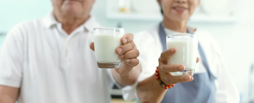 A man and women are both holding glasses of milk.